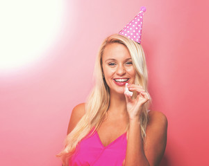 Wall Mural - Young woman with party theme on a pink background