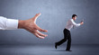 © ra2 studio - Young miniature businessman running from a big hand with blueish grey background