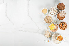 Selection Various Types Cereal Grains Groats  In Different Bowl On White Marble Background, Above Copy Space