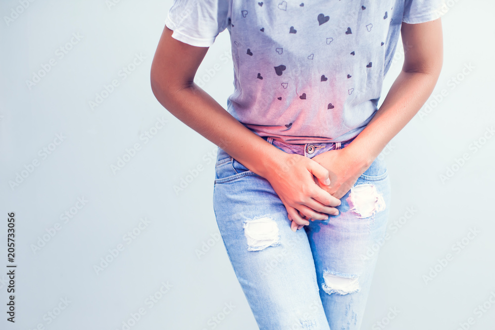 Young sick woman with hands holding pressing her crotch lower abdomen. Medical or gynecological problems, healthcare concept - obrazy, fototapety, plakaty 