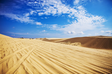  Sand dunes near Mui Ne. Group of off roads on top of dunes in the background. Sunny day with blue sky and clouds