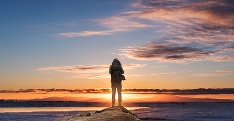 Wall Mural - a man with backpack standing on the rock enjoying sunrise in the morning