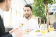 © pressmaster - Confident young man and his business partner or colleague having talk by lunch in restaurant