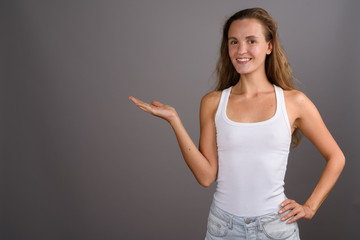 Young beautiful woman with long blond hair against gray backgrou