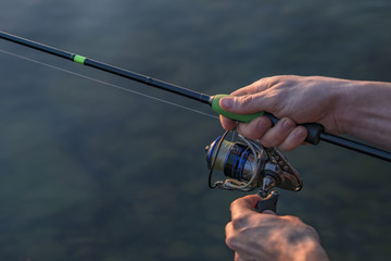 Hands of fisherman with fishing spinning rod