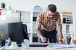 © Ivan Traimak - A man in the office is standing near the table and draws a marker on the magnetic board.