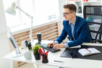 Young man sitting at desk in office and working on computer.