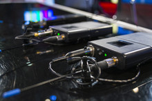 Three Wireless Microphone Transmitter And Three Wireless Microphone Reciever On Black Table In Tv Studio