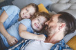 Outgoing little children embracing satisfied dad while resting together. Positive family concept