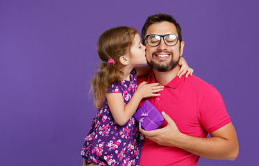 happy father's day! cute dad and daughter hugging on violet background.