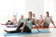 © New Africa - Group of people in sportswear practicing yoga indoors