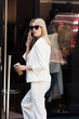 © LIGHTFIELD STUDIOS - beautiful young blonde woman in sunglasses talking by smartphone and drinking coffee to go