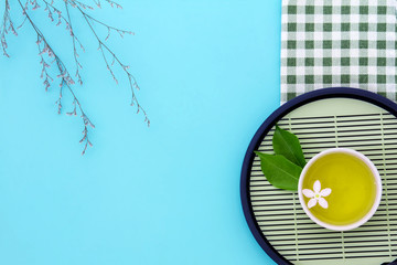 Poster - Top view shot of a hot cup of tea with green leaf decoration  with green napkin on blue background , Organic green Tea ceremony time concept