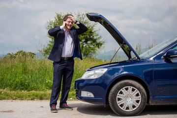 Wall Mural - A broken car on the road, a man talks to a cell phone and calls for help on the road