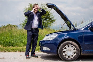 Wall Mural - A broken car on the road, a man talks to a cell phone and calls for help on the road