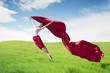 © Creativa Images - Asian woman ballerina holding red fabric making a big jump on meadow.
