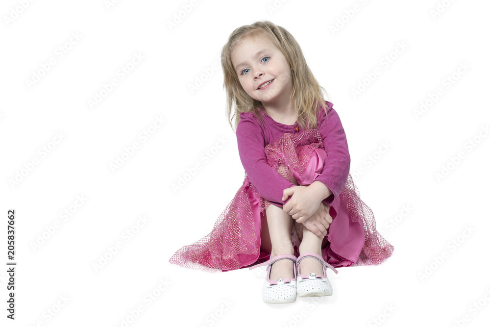 Portrait of little girl sitting on floor, hugging her knees, isolated