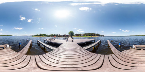 Wall Mural - full seamless panorama 360 by 180 angle view wooden pier for ships on huge forest lake in sunny summer day in equirectangular projection, skybox VR content. Wind of freedom