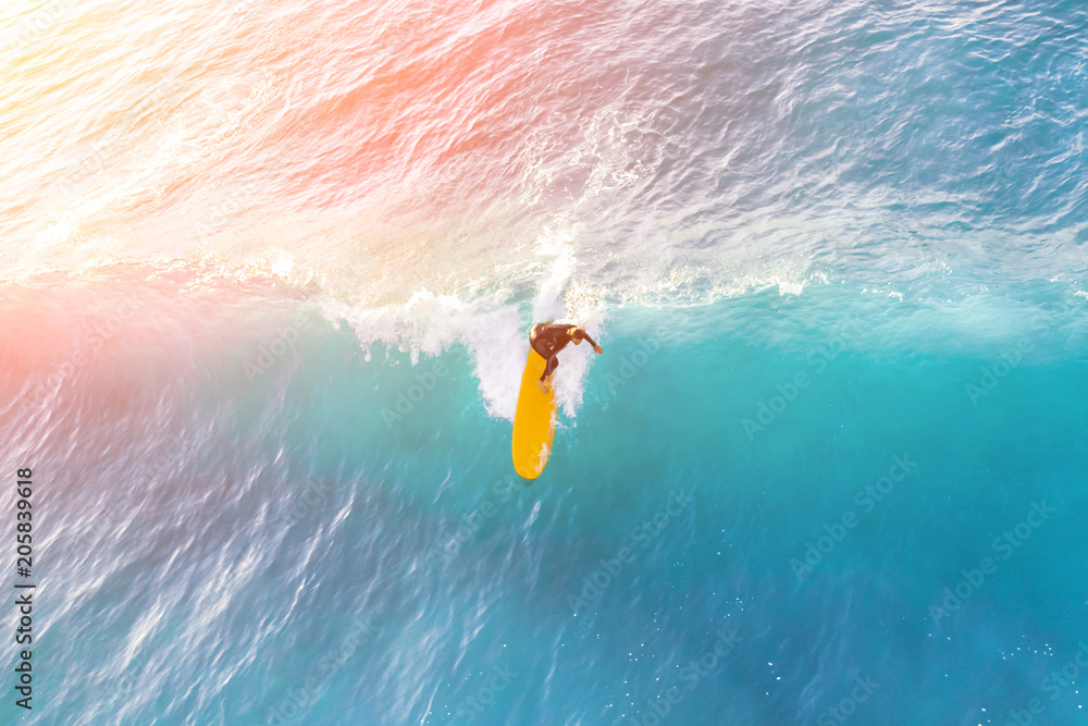 Surfer on a yellow surfboard in the ocean on a sunny day - obrazy, fototapety, plakaty 