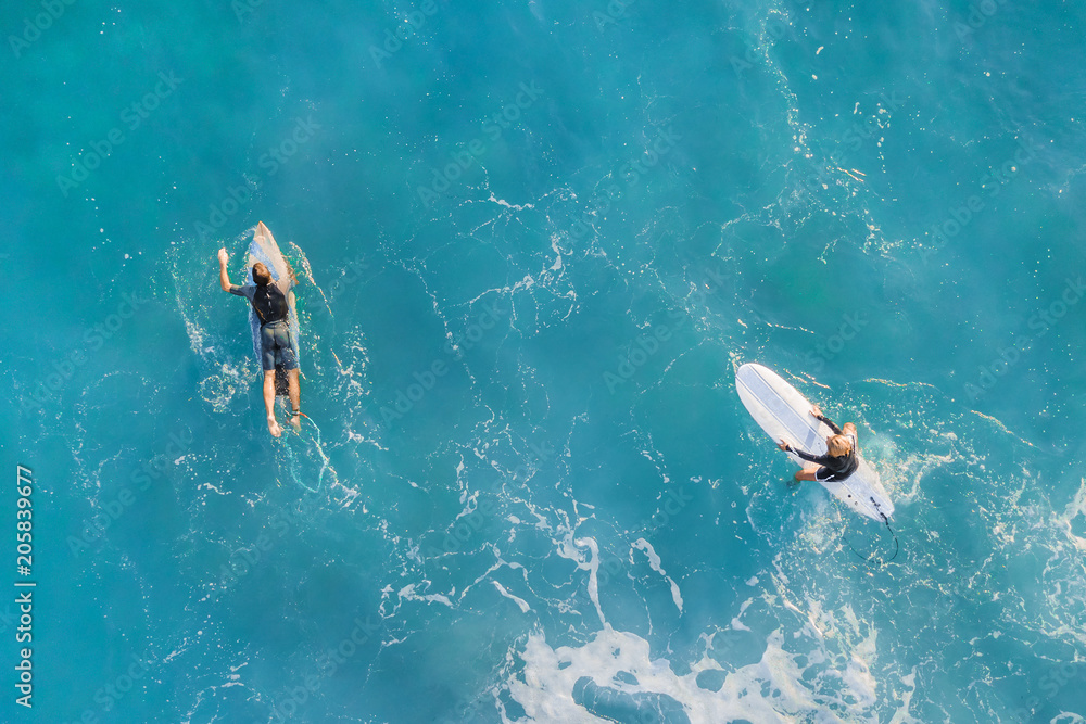 Two surfers in the ocean, top view - obrazy, fototapety, plakaty 