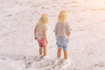 Two little blonde girls on the beach on a sunny day