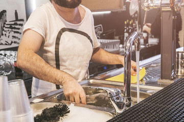 A man washes a glass in a restaurant