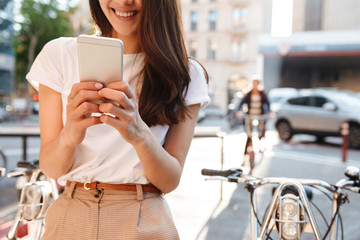 Poster - Woman walking outdoors on bicycle using mobile phone.