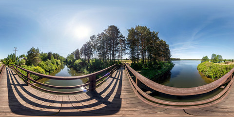 Wall Mural - full seamless panorama 360 by 180 angle view on wooden bridge across water canal against backdrop of huge lake in sunny summer day in equirectangular projection, skybox VR virtual reality content