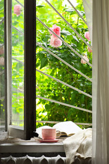 Wall Mural - Cup of coffee and book on windowsill against garden