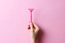 Razor In A Female Hand On A Colored Background. Removal Of Unwanted Hair. Minimalism, The Top