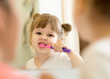 © Oksana Kuzmina - mother teaching her kid daughter teeth brushing