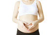 © Evrymmnt - Close up of pregnant woman wearing supportive seamless maternity bra & black yoga pants, arms on her belly. Female hands forming heart shape on stomach. Children's day concept. Background, copy space.