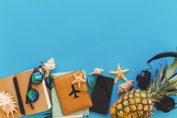 Wall Mural - summer vacation and travel flat lay. stylish black phone, passport, sunglasses, map, pineapple with headphones, shells,notebook on trendy blue paper. space for text.  wanderlust