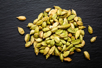 Poster - close up Organic cardamom pods on black slate stone background