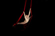 Joven bailarina realizando ejercicios de telas acrobáticas en estudio con fondo negro