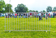 People behind a single metal barricade at a village event