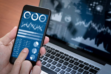 Investor analyzing stock market report and financial dashboard with business intelligence (BI), with key performance indicators (KPI).Businessman using smart phone with laptop computer.