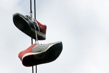 Two Old Sneakers Hang On Electric Wires. The Concept Is Time For A Vacation