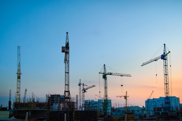 Canvas Print - Industrial landscape with silhouettes of constraction cranes on dramatic sunset background