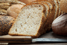 Heap Of Fresh Baked Bread With Knife On Wooden Background