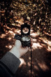 Mann hält einen Kompass in der Hand im dunklen Wald