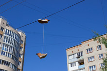 Old Sneakers On Wires Against The Blue Sky And Buildings