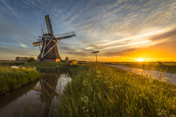 Wall Mural - Wooden windmill canal cycling track at sunset