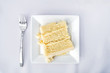 © Andriy Blokhin - Flat top table setting lay view down closeup of restaurant or wedding reception white table tablecloth one plate with vanilla cream cake slice, fork