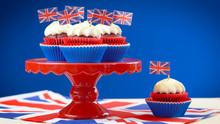 Red White And Blue Theme Cupcakes And Cake Stand With UK Union Jack Flags For Queen's Birthday Weekend Celebration Or Great Britain Party Food.