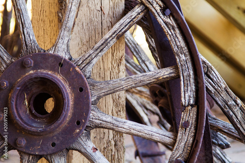 Cuadros en Lienzo Old wooden wagon wheel; antique wagon wheel resting against a post