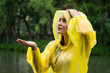 Young beautiful happy woman in yellow raincoat enjoying the rain
