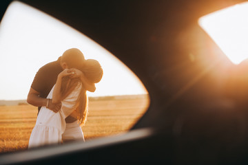 Wall Mural - Happy traveling couple.Sunny summer colors.Romantic mood.Happy mood.Young Couple Standing Next To Sport Car.Young couple in love 