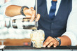 Detail of the hands of a bartender adding cocktail to a glass