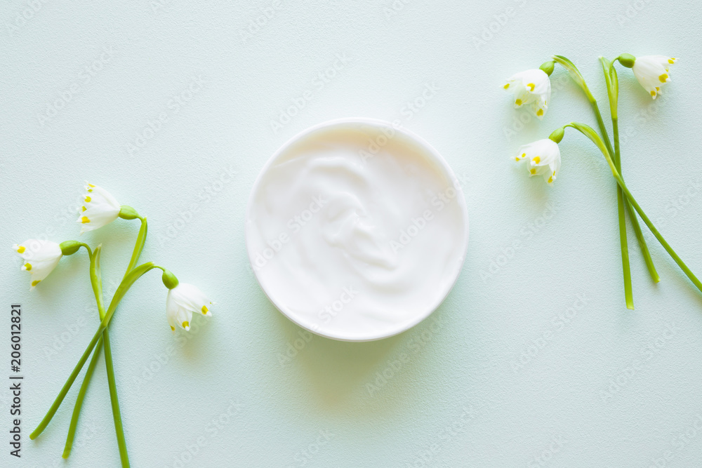 Jar of natural herbal cream for women. Beautiful, fresh snowdrop flowers. Care about clean and soft hands, legs and body skin. Top view. - obrazy, fototapety, plakaty 